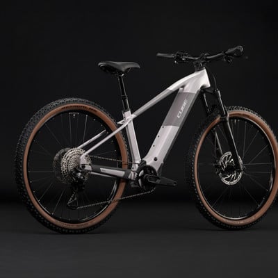 Graues E-Bike mit schwarzem Sattel und braunen Reifen auf schwarzem Hintergrund. Graues E-Bike mit schwarzem Sattel und braunen Reifen auf schwarzem Hintergrund.
