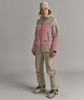 Eine Frau in einer Skijacke und Hose, trägt eine Mütze und Skischuhe.