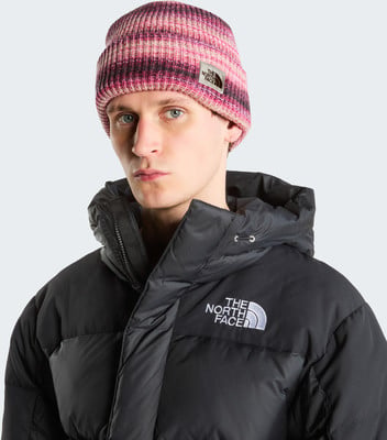 Ein Mann in einer pink-violett gestreiften Mütze und schwarzer Daunenjacke. Ein Mann in einer pink-violett gestreiften Mütze und schwarzer Daunenjacke.