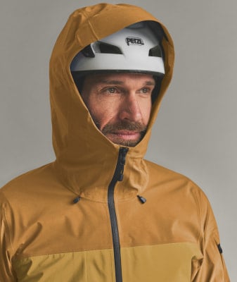 Ein Mann in einer gelben Kapuzenjacke und einem weißen Petzl-Helm. Ein Mann in einer gelben Kapuzenjacke und einem weißen Petzl-Helm.