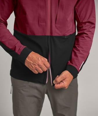 Ein Mann schließt eine dunkelweinrote Jacke mit schwarzem Unterteil. Ein Mann schließt eine dunkelweinrote Jacke mit schwarzem Unterteil.