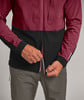 Ein Mann schließt eine dunkelweinrote Jacke mit schwarzem Unterteil.
