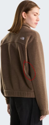 Eine Frau in einer braunen Jacke mit North Face Logo auf dem Rücken. Eine Frau in einer braunen Jacke mit North Face Logo auf dem Rücken.