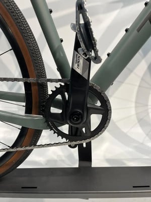 Nahaufnahme der Kurbel und Kette eines Gravelbikes mit SRAM APEX Logo. Nahaufnahme der Kurbel und Kette eines Gravelbikes mit SRAM APEX Logo.