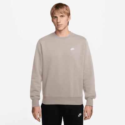 Mann in grauem Nike Sweatshirt mit Logo auf der Brust und schwarzer Hose. Mann in grauem Nike Sweatshirt mit Logo auf der Brust und schwarzer Hose.