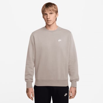 Mann in grauem Nike Sweatshirt mit Logo auf der Brust und schwarzer Hose.