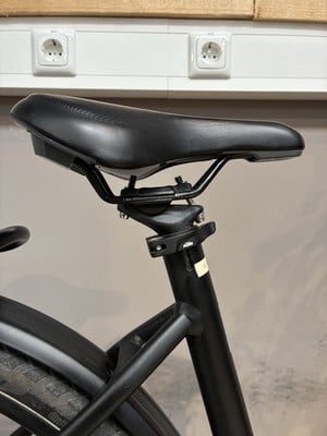 Schwarze Sattelstütze mit schwarzem Sattel auf einem Fahrrad, Steckdosen im Hintergrund. Schwarze Sattelstütze mit schwarzem Sattel auf einem Fahrrad, Steckdosen im Hintergrund.