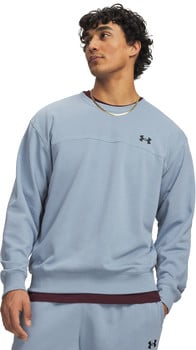 Ein Mann in einem blauen Sweatshirt mit schwarzem Under Armour Logo und einer goldenen Kette.