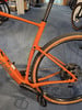 Ein orangefarbenes Fahrrad mit braunen Reifen und schwarzer Sattelstütze.