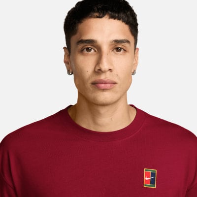Ein Mann in einem dunkelroten T-Shirt mit Nike-Logo auf der Brust.
