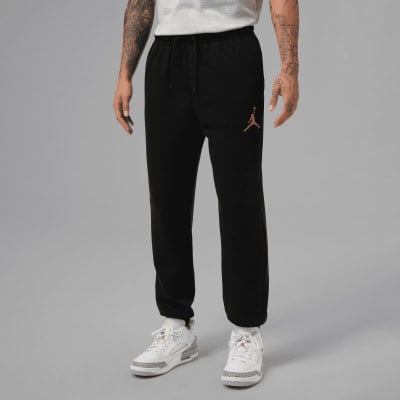 Mann in schwarzer Jogginghose mit Jordan-Logo und weißen Turnschuhen Mann in schwarzer Jogginghose mit Jordan-Logo und weißen Turnschuhen