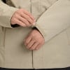 Nahaufnahme eines Mannes, der einen Klettverschluss am Ärmel einer beige Jacke anpasst.