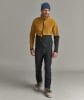 Ein Mann in Skibekleidung mit Jacke und Hose, trägt eine blaue Mütze.