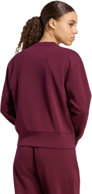 Frau in dunkelweinfarbener Sportkleidung mit Pferdeschwanz.