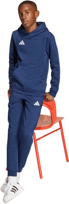 Ein junger Junge in einem dunkelblauen Adidas-Anzug sitzt auf einem roten Stuhl. Ein junger Junge in einem dunkelblauen Adidas-Anzug sitzt auf einem roten Stuhl.