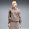 Frau in einem beigen Kapuzenpullover und Jogginghose.