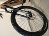 Ein goldenes Mountainbike mit Federung und schwarzen Felgen auf grauem Untergrund.