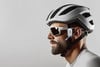 Ein Mann mit Fahrradhelm und Brille trägt ein Sena-Kommunikationsgerät am Ohr.
