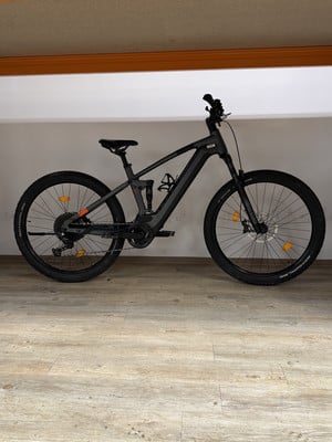 Schwarzes Mountain-E-Bike mit Federung und Scheibenbremsen auf Holzboden. Schwarzes Mountain-E-Bike mit Federung und Scheibenbremsen auf Holzboden.
