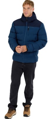 Egy férfi sötétkék pehelydzsekiben és fekete nadrágban áll. Egy férfi sötétkék pehelydzsekiben és fekete nadrágban áll.