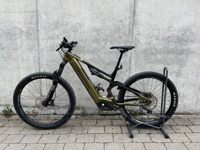 Ein grünes E-Mountainbike mit Federung, das an einer Wand geparkt ist. Ein grünes E-Mountainbike mit Federung, das an einer Wand geparkt ist.