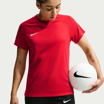 Eine Frau in einem roten T-Shirt hält einen Fußball.