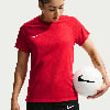 Eine Frau in einem roten T-Shirt hält einen Fußball.