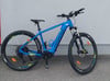 Ein blaues Genesis E-Mountainbike mit schwarzen Reifen und gelben Akzenten.