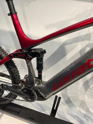Detail des hinteren Teils eines rot-grauen E-Bikes mit Dämpfer und Antrieb.