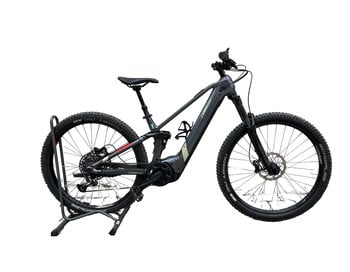 Graues E-Mountainbike auf Ständer vor weißem Hintergrund.