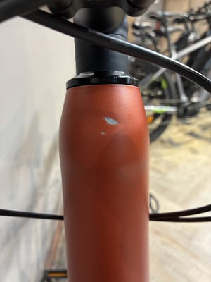 Auf dem orangefarbenen Fahrradrahmen sind leichte Abnutzungen und Kratzer sichtbar. Auf dem orangefarbenen Fahrradrahmen sind leichte Abnutzungen und Kratzer sichtbar.