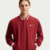 Ein Mann in einer dunkelroten Nike-Jacke mit weißem Logo und Streifen.