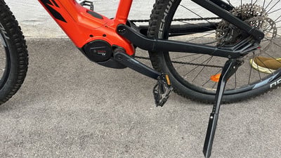 Nahaufnahme eines E-Bikes mit orangefarbenem Rahmen und schwarzen Komponenten. Nahaufnahme eines E-Bikes mit orangefarbenem Rahmen und schwarzen Komponenten.
