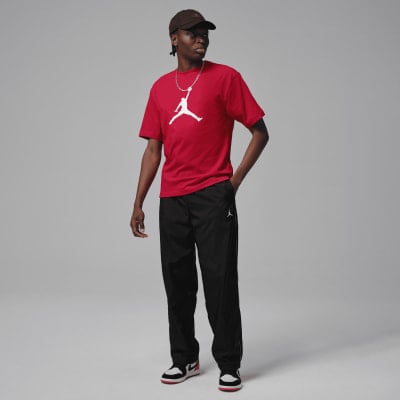 Ein Mann in einem roten Jordan-T-Shirt und schwarzer Hose mit Schuhen. Ein Mann in einem roten Jordan-T-Shirt und schwarzer Hose mit Schuhen.