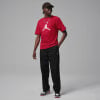 Ein Mann in einem roten Jordan-T-Shirt und schwarzer Hose mit Schuhen.