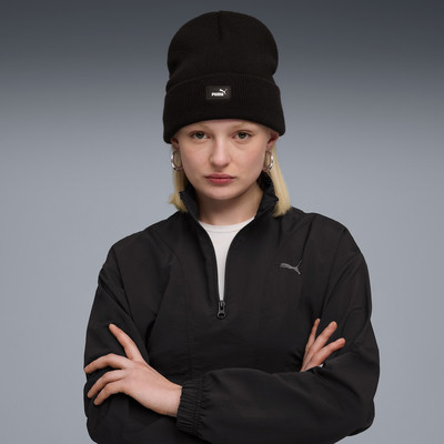 Eine Frau in einer schwarzen Mütze und Jacke mit Puma-Logo, die Arme vor der Brust verschränkt. Eine Frau in einer schwarzen Mütze und Jacke mit Puma-Logo, die Arme vor der Brust verschränkt.