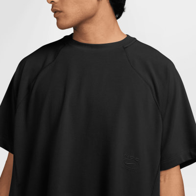 Ein Mann in einem schwarzen T-Shirt mit Nike-Logo auf der Brust. Ein Mann in einem schwarzen T-Shirt mit Nike-Logo auf der Brust.