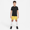 Junge in schwarzem T-Shirt und gelben Shorts mit weißen Socken.