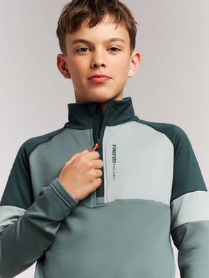 Junge in dunkelgrünem Pullover mit Reißverschluss und Logo