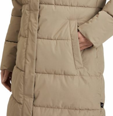 Detail einer Damen-Steppjacke in Beige mit einer Tasche, in die eine Hand gesteckt ist. Detail einer Damen-Steppjacke in Beige mit einer Tasche, in die eine Hand gesteckt ist.