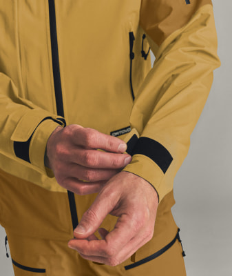 Ein Mann schließt den Klettverschluss am Ärmel einer Jacke. Ein Mann schließt den Klettverschluss am Ärmel einer Jacke.