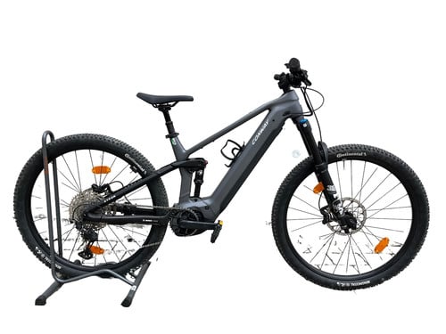 Graues E-Mountainbike auf einem Ständer mit Federung vorne und hinten.