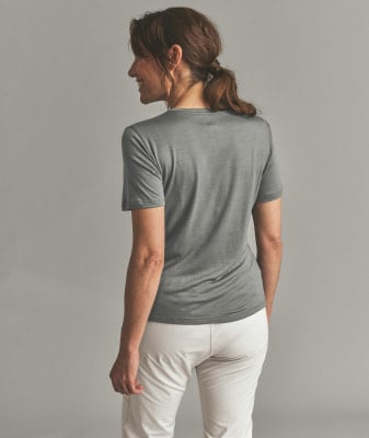 Eine Frau in einem grauen T-Shirt und weißer Hose steht mit dem Rücken zur Kamera. Eine Frau in einem grauen T-Shirt und weißer Hose steht mit dem Rücken zur Kamera.