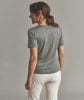 Eine Frau in einem grauen T-Shirt und weißer Hose steht mit dem Rücken zur Kamera.