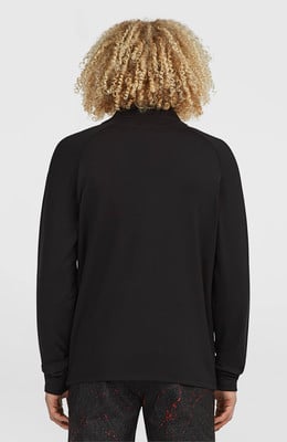 Ein Mann mit lockigem Haar von hinten in einem schwarzen Langarmshirt.