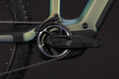 Detail eines E-Bikes mit Kette, Kurbel und Kettenblatt vor dunklem Hintergrund.