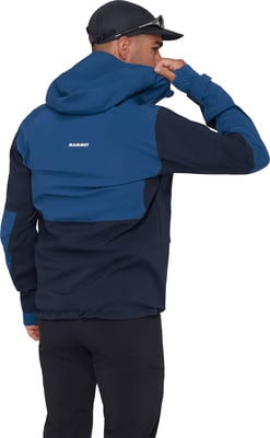 Ein Mann in einer dunkelblauen Kapuzenjacke und schwarzer Hose passt seine Kapuze an.