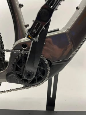 Detailaufnahme der Kurbeln und Kette eines E-Bikes mit glänzendem Rahmen. Detailaufnahme der Kurbeln und Kette eines E-Bikes mit glänzendem Rahmen.