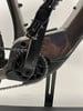 Detailaufnahme der Kurbeln und Kette eines E-Bikes mit glänzendem Rahmen.