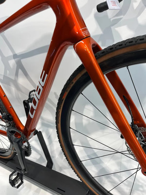 Orangefarbenes Gravelbike mit CUBE-Logo und Rahmenbeschriftung. Orangefarbenes Gravelbike mit CUBE-Logo und Rahmenbeschriftung.